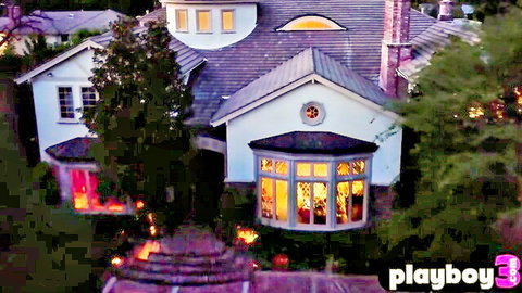 Luxurious Playboy mansion exterior at night with warm glowing windows
