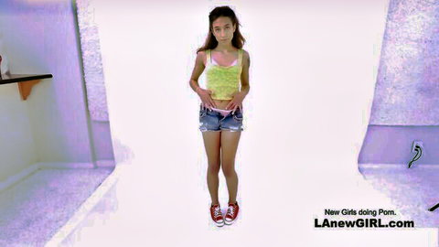 New brunette girl posing in yellow tank top and denim shorts