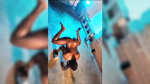 Nude ebony woman in upside-down calisthenics pose, muscular body flexing