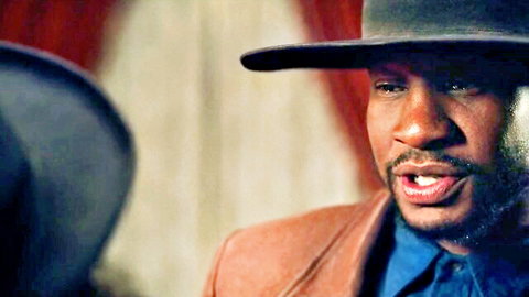 Idris Elba lookalike in suit and hat, intense gaze from The Harder They Fall scene