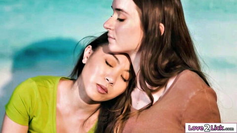 Two women embracing intimately, one in green top resting on brunette in brown top