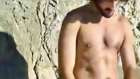 Bearded muscular twink posing nude on rocky beach