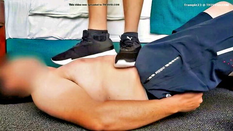 Woman trampling shirtless man with Puma sneakers in foot fetish