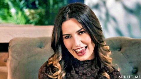 Chanel Camryn, brunette teen smiling playfully with tongue out in brown sweater