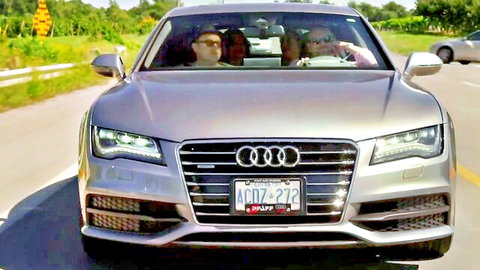 Silver Audi A7 driving on scenic road with passengers inside