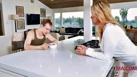 Blonde step-sis in white top leans on counter teasing step-bro at kitchen table