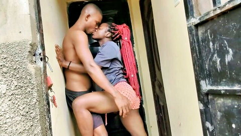 Muscular black guy passionately kissing dreadlocked ebony babe against wall in amateur outdoor embrace