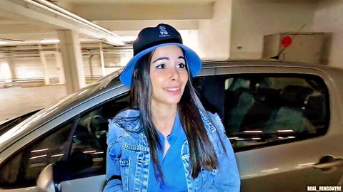 Smiling Latina stepmom in denim jacket and hat by car in parking lot