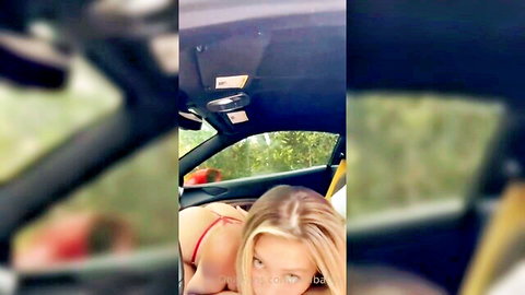 Blonde babe in skimpy red thong bikini leaning back seductively in open sports car seat