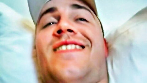 Smiling young man in backwards cap lying on pillows looking up