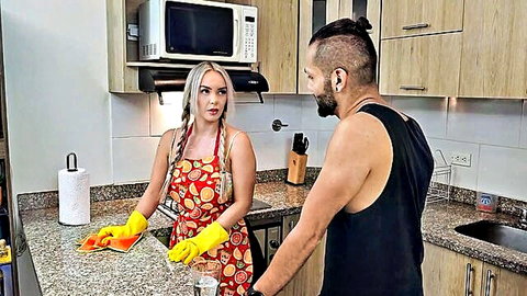 Blonde in sexy apron and gloves cleans kitchen with muscular man watching