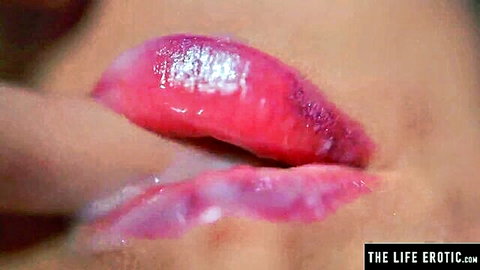 Close-up of glossy red lips touched by finger in erotic solo tease