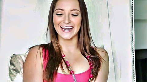 Smiling brunette with long hair and medium tits showing deep cleavage in tight pink top