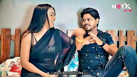 Sexy Indian woman in black saree blouse shows deep cleavage laughing intimately with man on bed