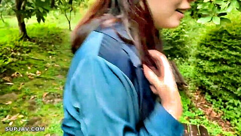Smiling Asian woman with long brown hair in blue top outdoors