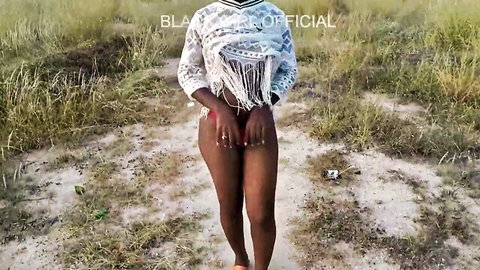 Black woman in fringed white top teases in public field exhibitionism