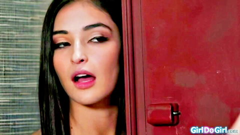 Seductive brunette teen peeking from red locker with glossy pink lips parted for lesbian pussy licking