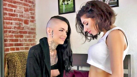 Tattooed shaved-head punk lesbian seduces brunette lifting white crop top to tease underboob passionately