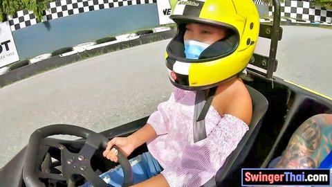 Thai teen in yellow helmet driving go-kart, off-shoulder top, tattooed arm