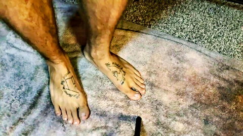 Hairy male feet with intricate tattoos, close-up in steamy anal dance scene