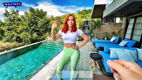 Curvy redhead in tight green leggings and crop top waves teasingly by infinity pool