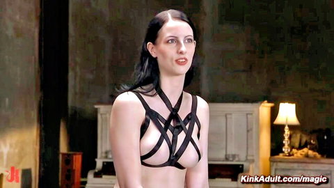 Bound woman in black harness exposing breasts in BDSM scene