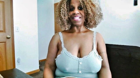 Smiling ebony MILF with huge tits spilling from low-cut lace tank top