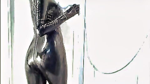 Curvy woman in shiny black latex catsuit, rear view emphasizing big ass in piss fetish solo