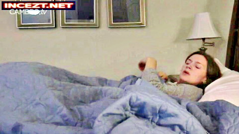 Brunette MILF moaning passionately in bed under blue blanket on webcam