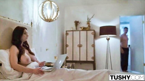 Topless brunette with big tits in bed on laptop, man peeking before anal fuck
