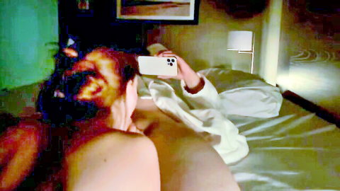Curvy redhead taking nude selfie on bed, showing ass from behind