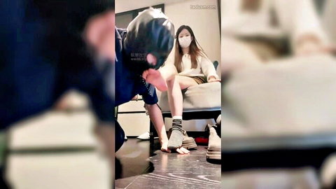 Asian woman in mask seduces kneeling man with socked foot tease