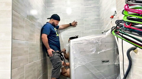 Muscular guy in cap with hard cock gets blowjob from kneeling Latina in cramped laundry room