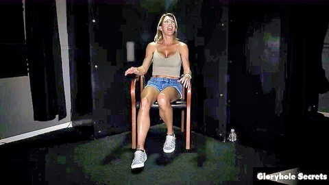 Blonde MILF in tight top and shorts sits in gloryhole booth with mouth open ready for BBC blowjob