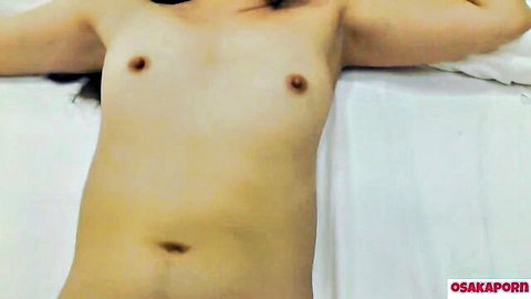 Topless Asian Korean woman lying on bed with small perky breasts exposed