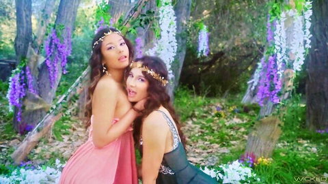 Two sexy brunettes in skimpy dresses embrace playfully in enchanted wisteria forest garden