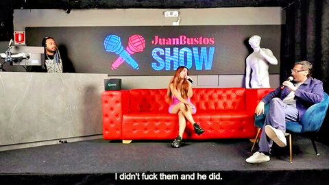Brunette in pink mini dress on Juan Bustos Show couch with 'I didn't fuck them and he did' text overlay