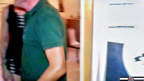 Mature man in green striped polo shirt stands in bathroom near pink high heel and blue chair
