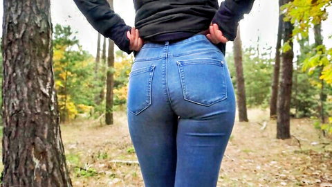 Brunette teen shows off big round ass in tight blue jeans in forest