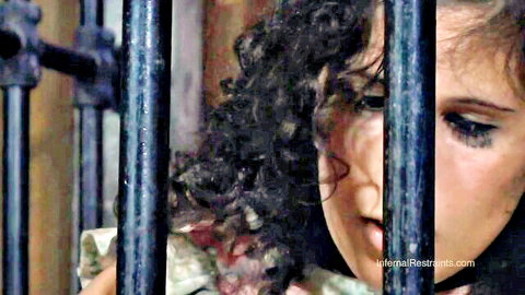 Marina in BDSM restraints, curly-haired beauty peering through bars