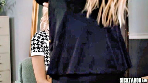 Blonde woman in black polka-dot dress teasing over shoulder in mirror