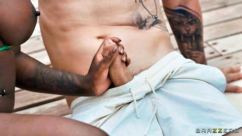 Tattooed ebony woman grips white guy's thick cock through pulled-down white shorts poolside