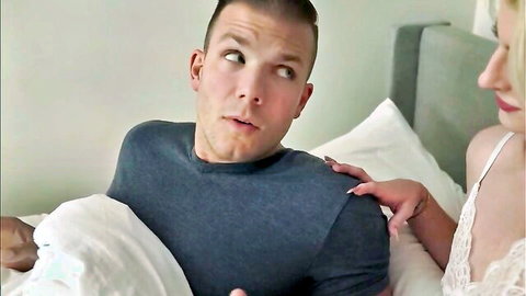 Surprised short-haired guy in t-shirt stares as hot blonde in lace lingerie touches him in bed