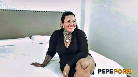 Curvy Spanish mature woman in low-cut black dress showing big tits and tattoos