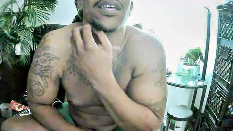 Shirtless muscular Latino man Mufasa520 smiling with tattoos and dreads
