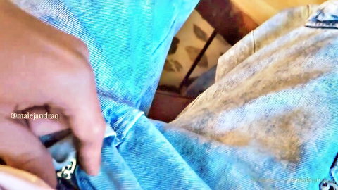 Dark-skinned hand unzipping tight blue jeans teasing crotch in living room