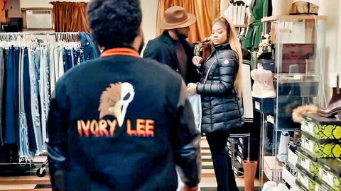 Ebony woman in puffy jacket chatting with black men wearing Ivory Lee jacket in clothing store