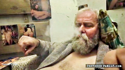 Pervy old bearded man smoking cigar with hairy chest bare amid nude women and ass posters