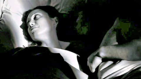 Nude woman with small tits lying relaxed in bed as man's hand grips her side
