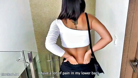 Daniela Antury in pain, hands on lower back, sexy white top and tight pants